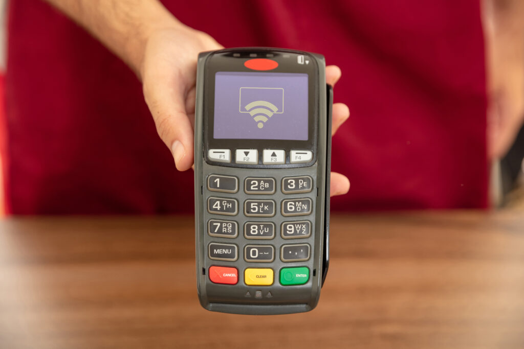 Cashier offering POS terminal for payment with credit card.